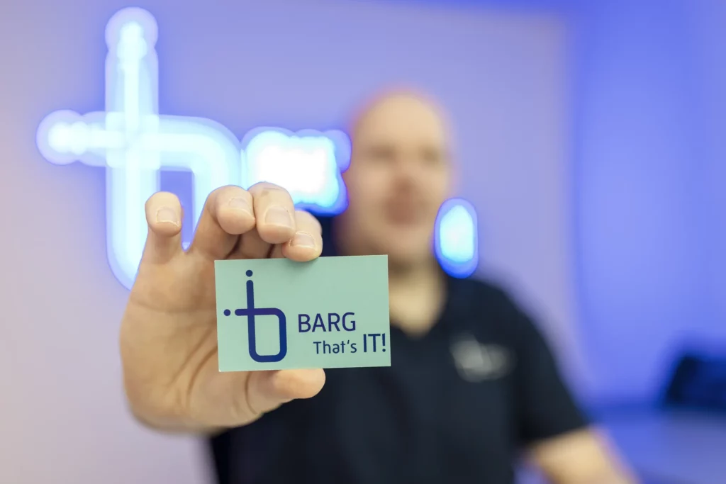 Mann hält grüne Visitenkarte mit Logo in die Kamera, Hintergrund unscharf