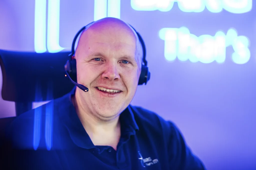 Nahaufnahme eines Mannes mit Headset vor blau beleuchtetem Hintergrund