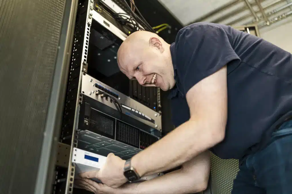 Mann arbeitet mit Messgerät an offenem Serverschrank