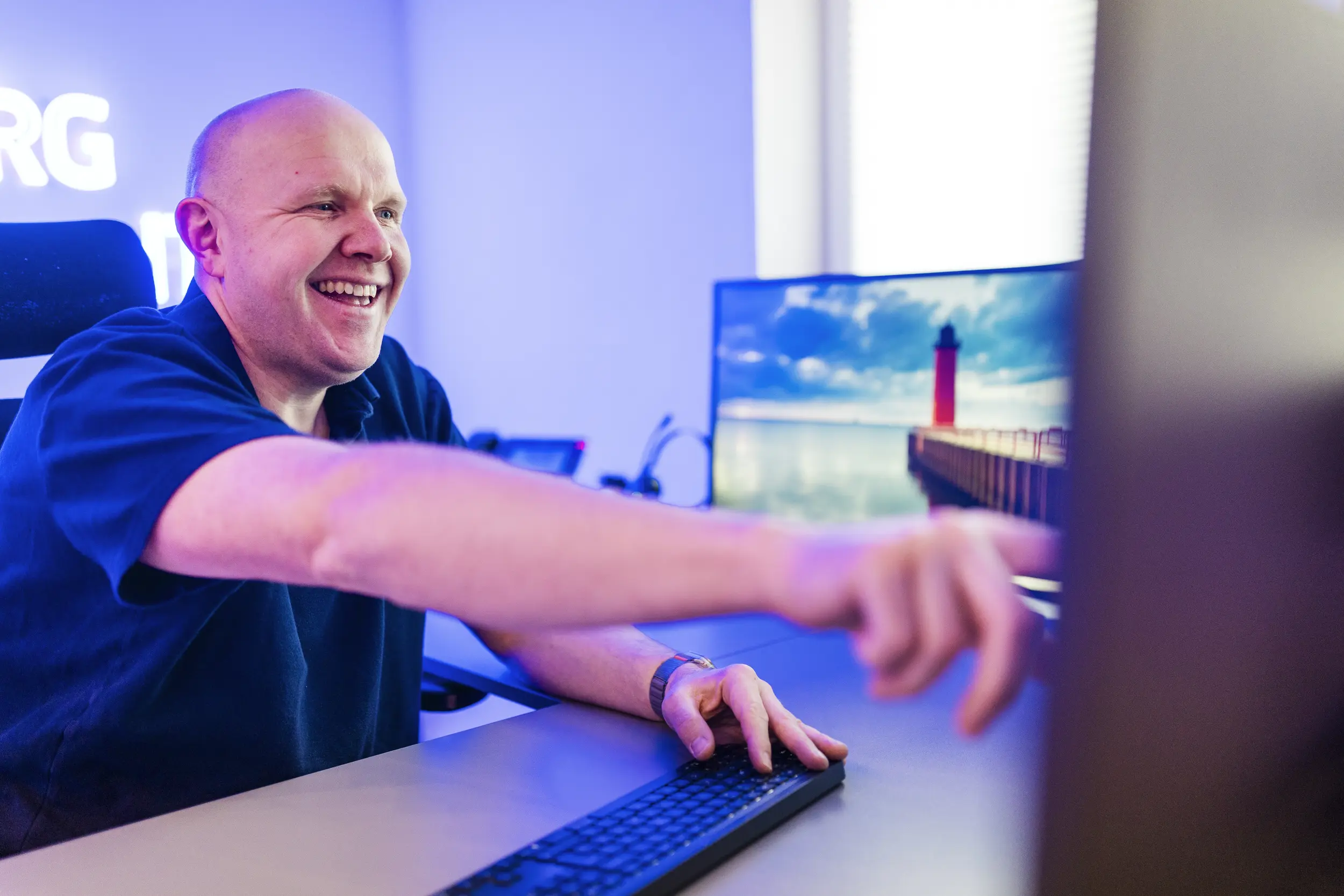 Mann zeigt lachend auf einen Computerbildschirm